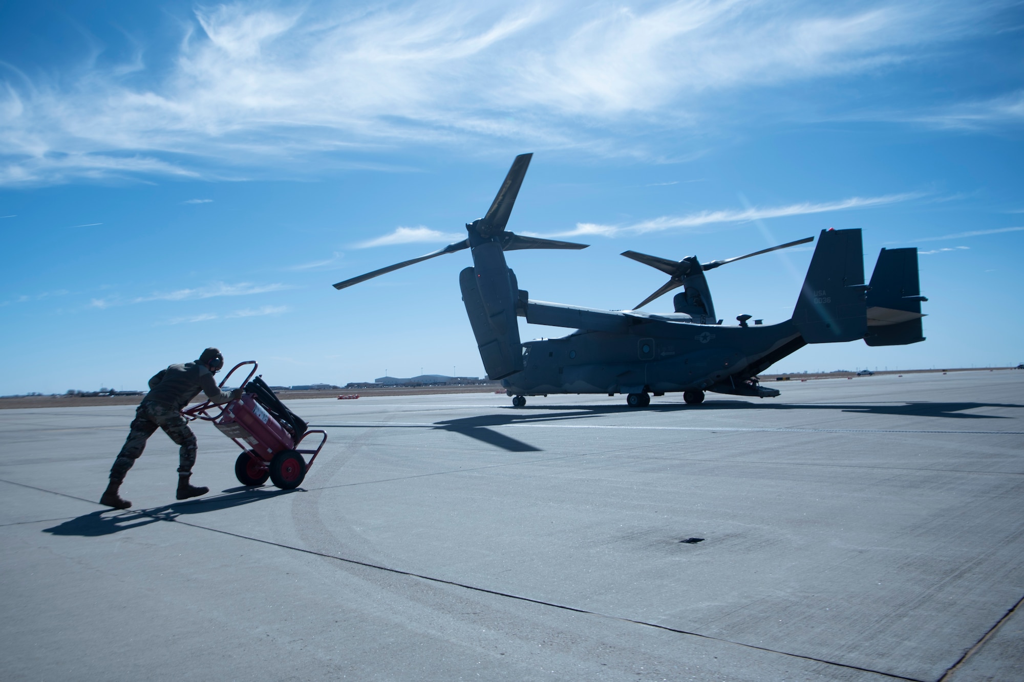 An Airman pushes a cart towards a plane before refueling it