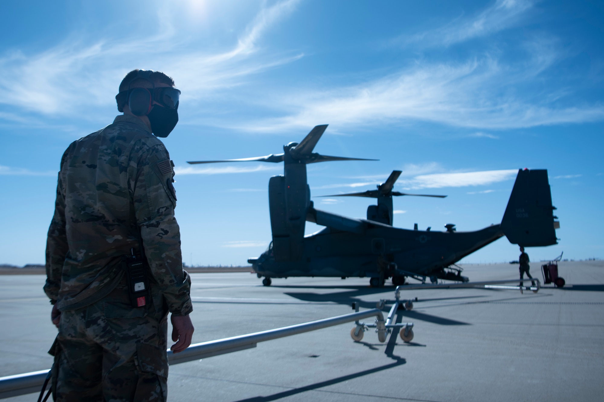 An Airman stands on the left as he fuels a CV-22 Osprey