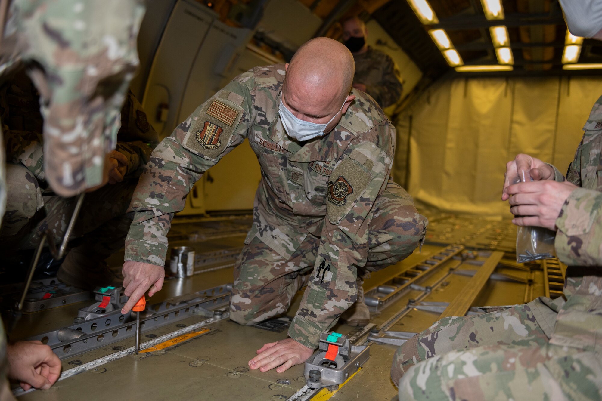 U.S. Air Force Chief Master Sgt. Robert Schultz, 60th Air Mobility Wing command chief, unscrews a floorboard during Leadership Rounds Jan. 8, 2021, at Travis Air Force Base, California. The Leadership Rounds program provides 60th AMW leadership an opportunity to interact with Airmen and receive a detailed view of each mission performed at Travis AFB. (U.S. Air Force photo by Senior Airman Cameron Otte)