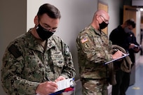 JOINT BASE LANGLEY-EUSTIS (January 11, 2021) Joint Task Force Civil Support Surgeon General Navy Capt. Dirk Warren, Operations Director Army Col. Christopher Caldwell and Dustin Bryson, of the command’s J6 directorate, fill out screening paperwork while waiting to receive the COVID-19 vaccination at McDonald Army Health Center.