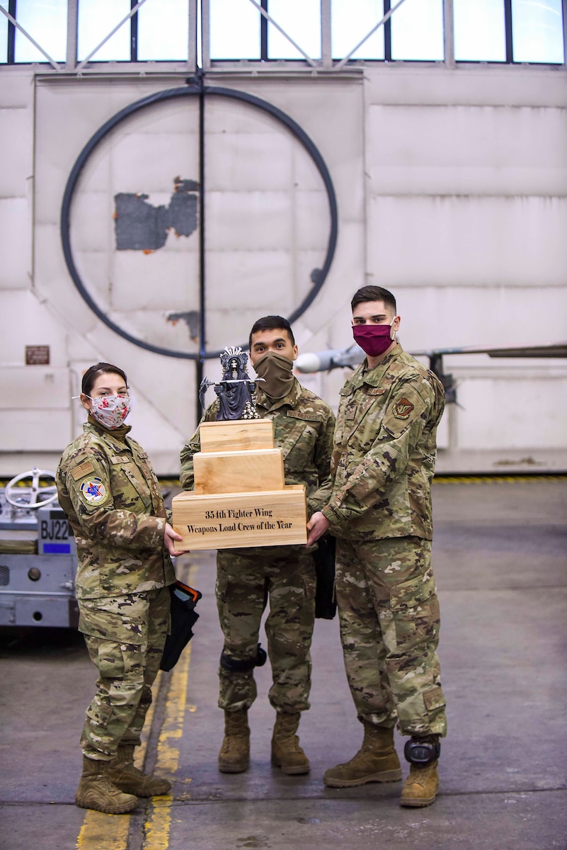 Staff Sgt. Rachelle Bellini, Senior Airman Ruben Moreno, and Senior Airman Nathan Furr, 18th Munitions Unit load crew competition winners stand with their trophy Jan. 8, 2021, on Eielson AFB, Alaska. Every three months there’s a load crew competition and the winners of the quarterly challenges will face off at an annual competition. (U.S. Air Force photo by Senior Airman Keith Holcomb)