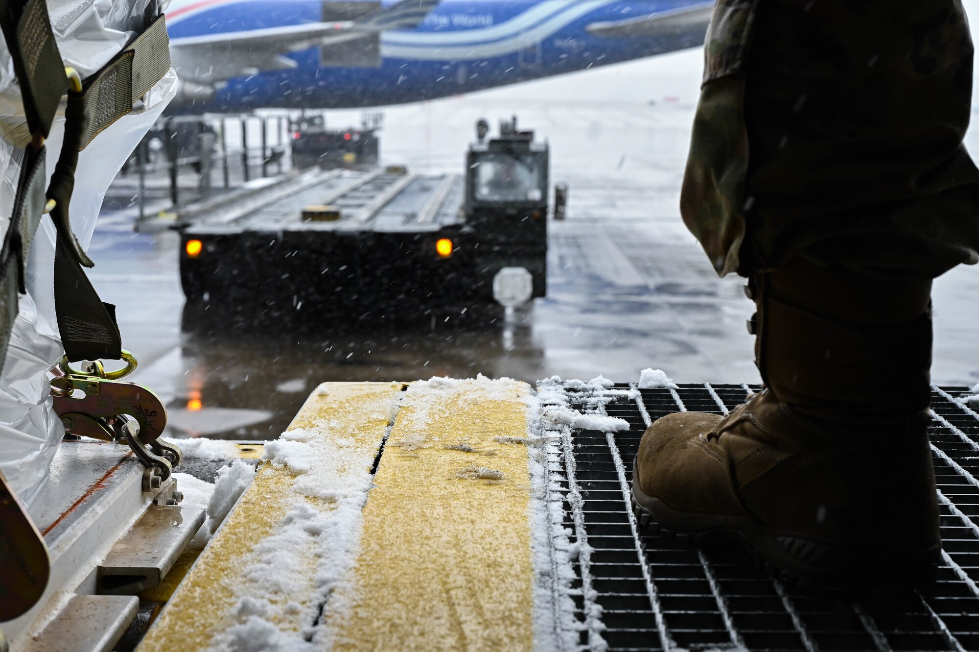 An Airman guides a loader toward a loading dock.