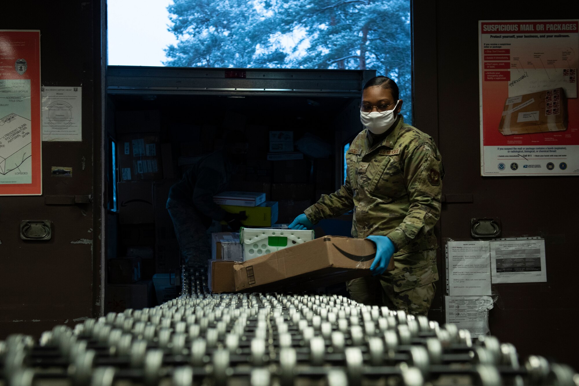 A photo of an Airman taking packages off a conveyor belt.