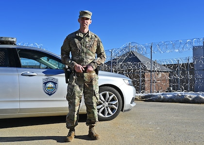1st Lt. James Lawrence, a military police officer with the 237th MP Company, NHARNG, poses with his issued corrections patrol car on the perimeter of the state prison Jan. 10, 2021, in Concord, N.H