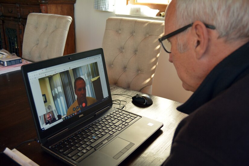 An elderly man speaks with a doctor during a virtual health meeting.