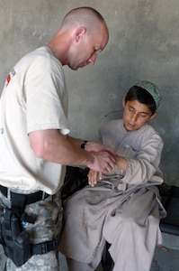 A Soldier gives medical attention to a boy