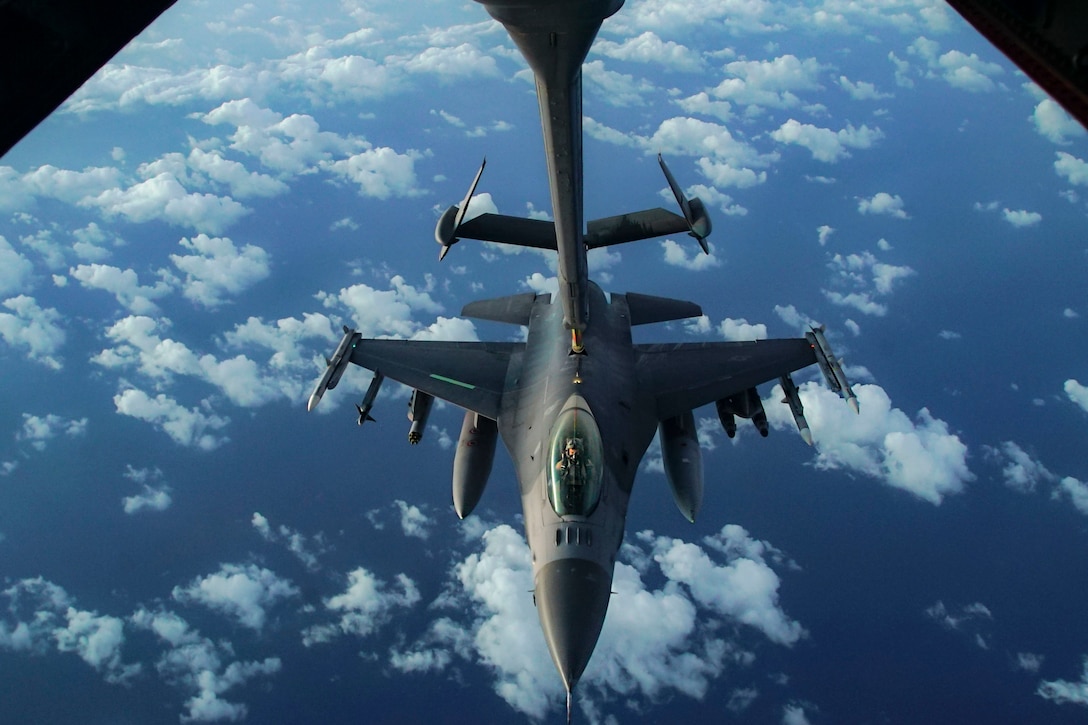 A fighter jet is refueled in midair.