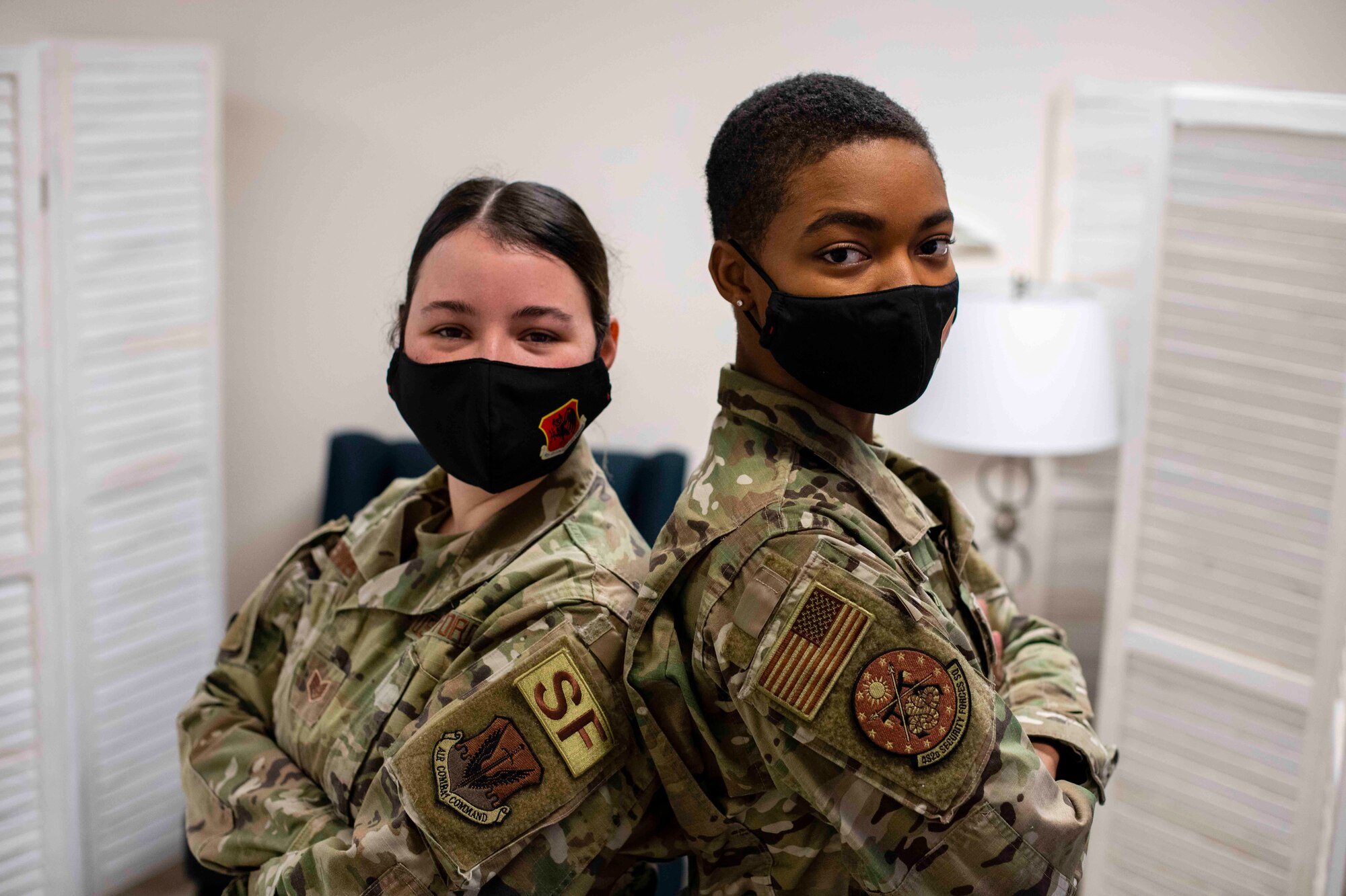 Staff Sgt. Kimberly and Staff Sgt. Laymisha, 432nd Security Forces Squadron Defenders, pose for a photo back to back while looking at the camera.