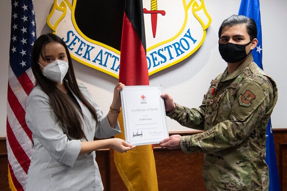 Jocelynn Cobb, Spangdahlem Red Cross regional program manager (left), presents U.S. Air Force Senior Airman Ezekiel Lopez, 52nd Force Support Squadron fitness center journeyman, with the Red Cross Certificate of Merit.