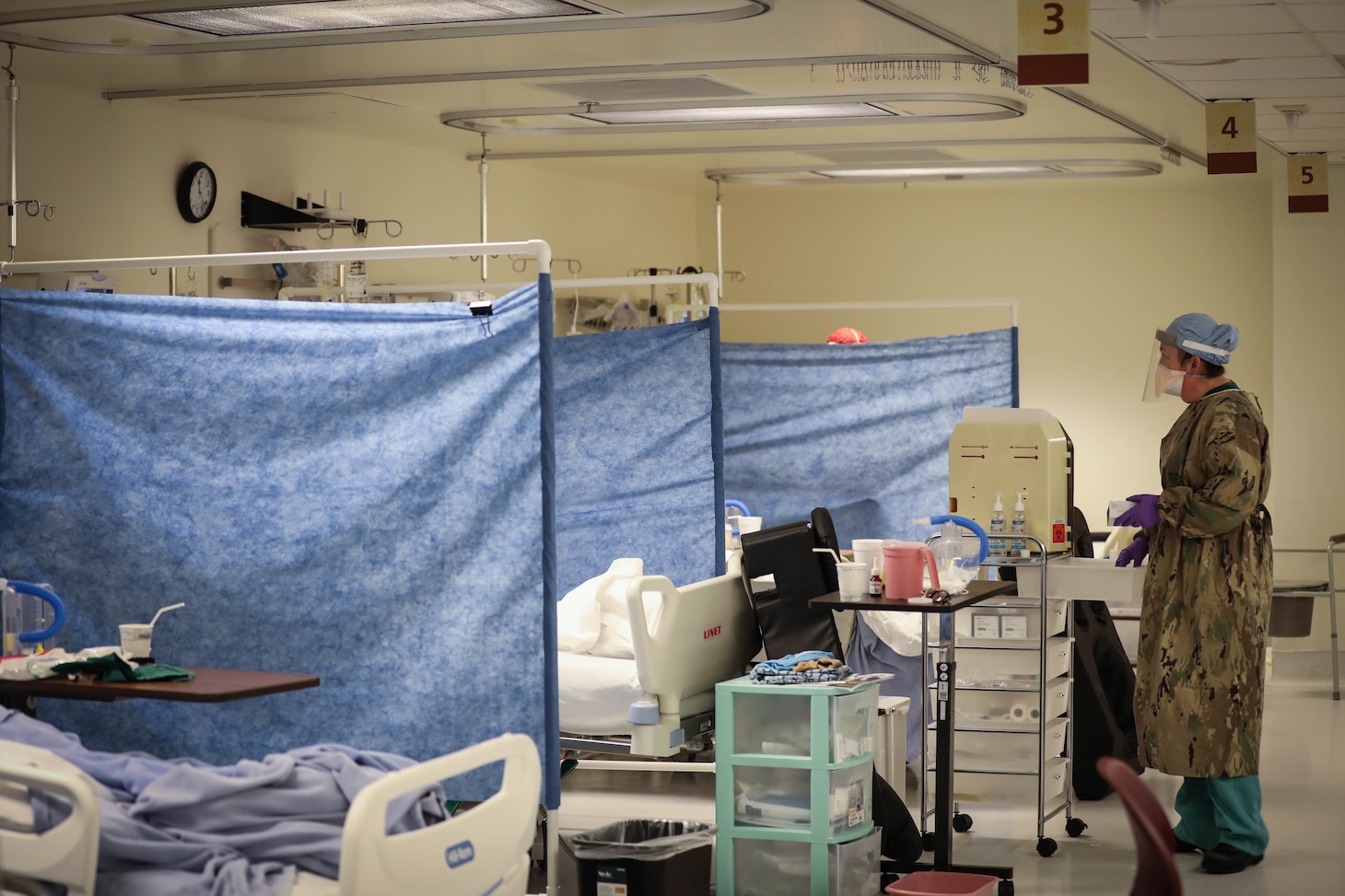 A nurse checks on multiple patients.