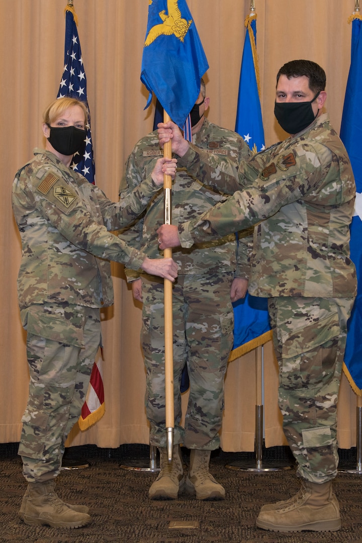 Two Airmen hold a flag during a military change of command ceremony