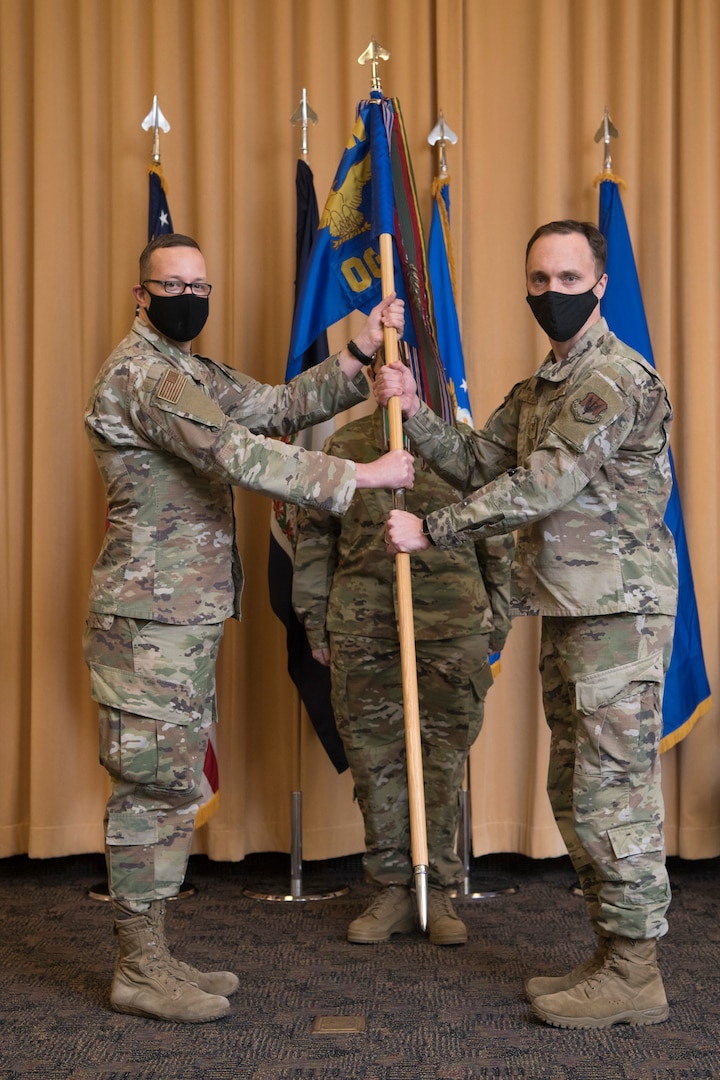 Two Airmen hold a flag during a military change of command ceremony