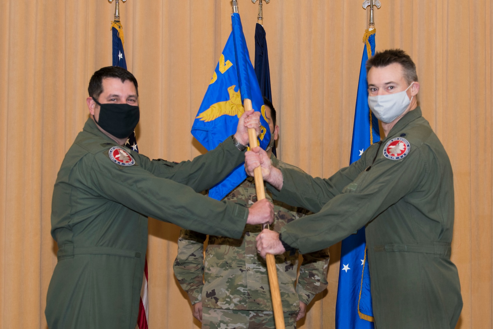 Two Airmen hold a flag during a military change of command ceremony