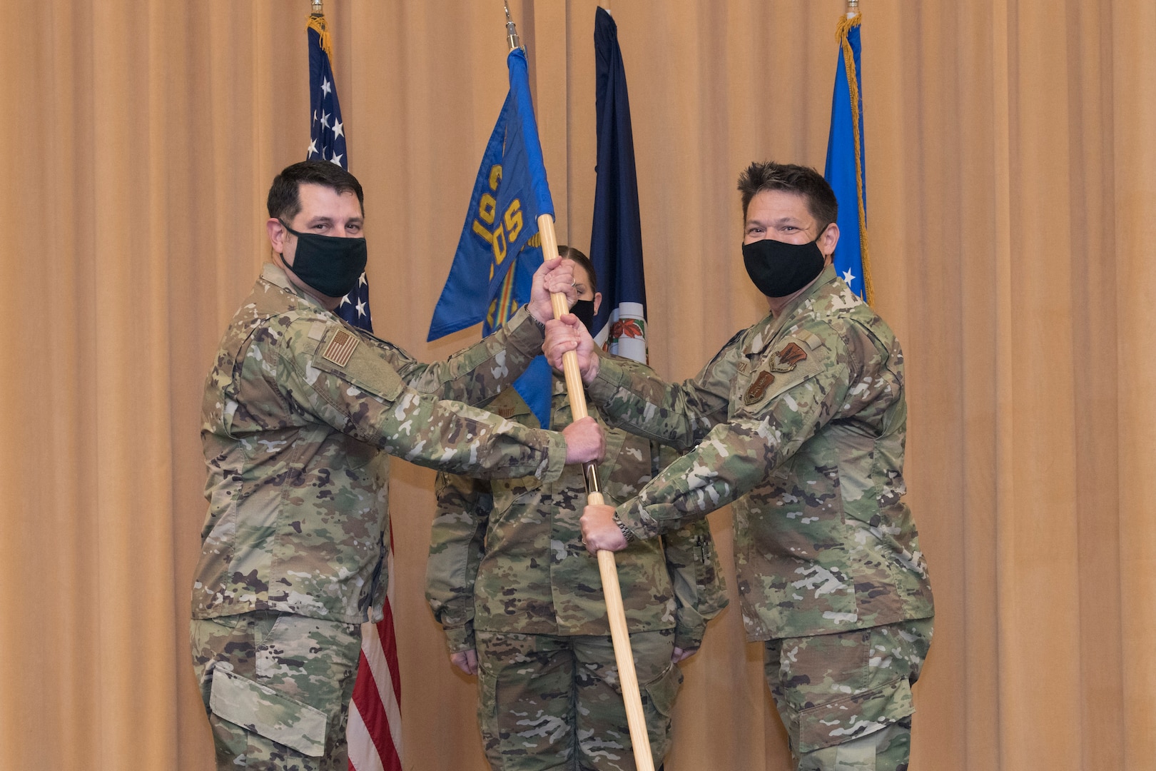 Two Airmen hold a flag during a military change of command ceremony