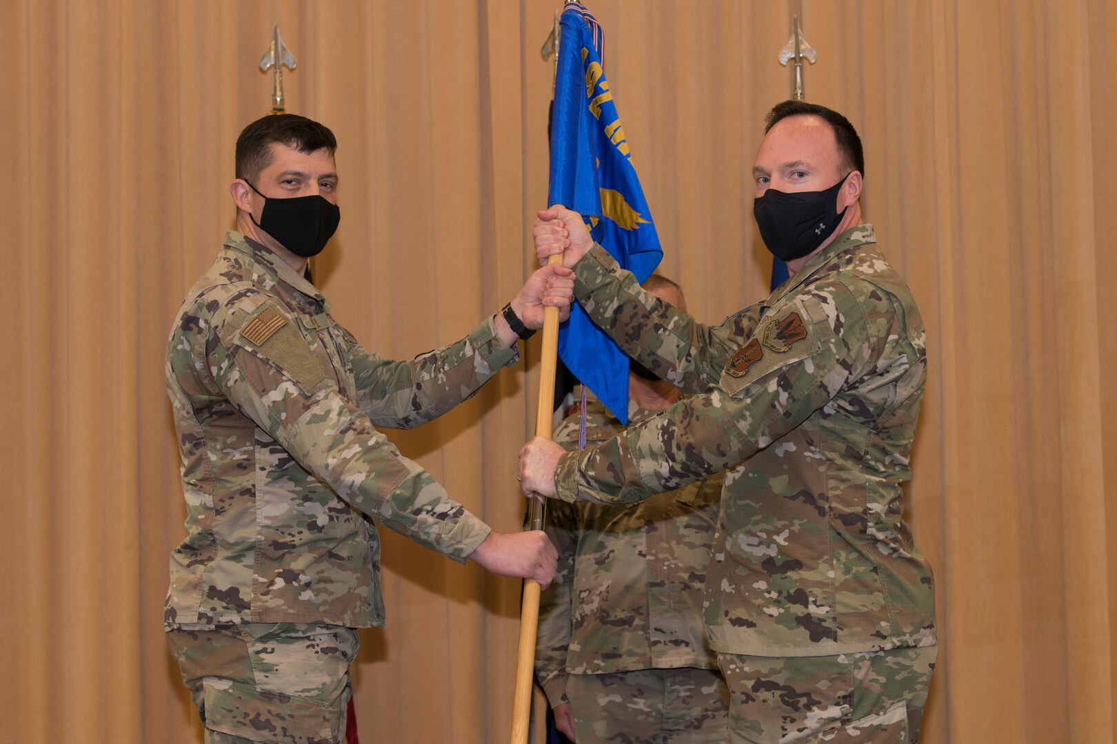 Two Airmen hold a flag during a military change of command ceremony