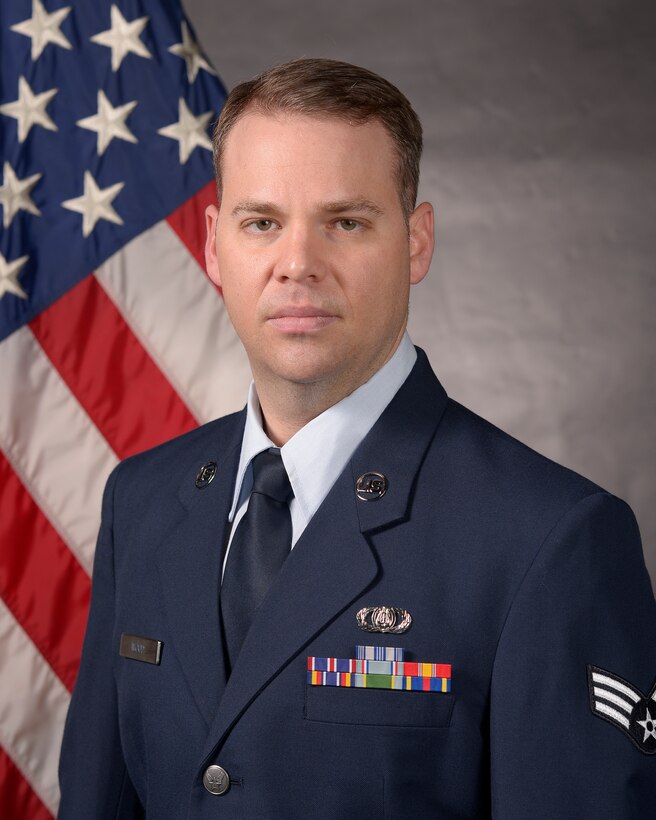 an airman poses in front of flag