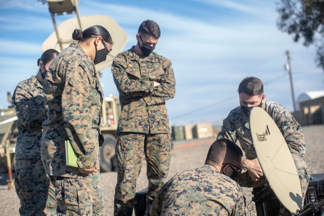 Five Marines work on a satellite dish.