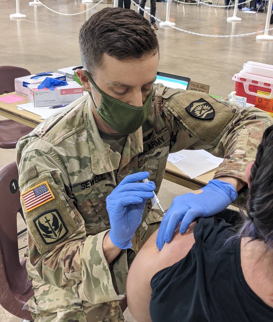 Oregon National Guard Spc. Toby SeWell vaccinates a Salem resident at the Oregon State Fairgrounds in Salem, Ore., Jan. 13, 2021. The Oregon National Guard was activated by Oregon Gov. Kate Brown on Jan. 8 to assist with the state vaccination efforts.