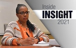 Woman sitting in a chair wearing a brown and orange sweater takes notes during a meeting