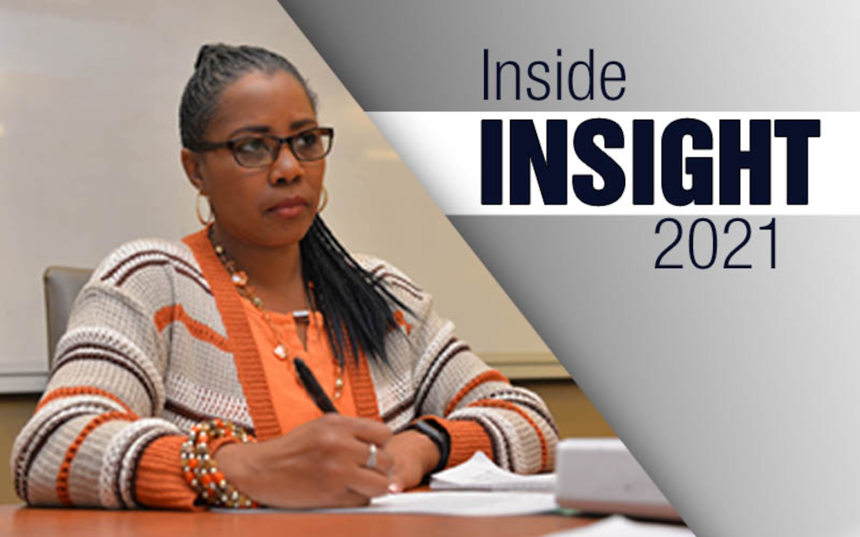 Woman sitting in a chair wearing a brown and orange sweater takes notes during a meeting