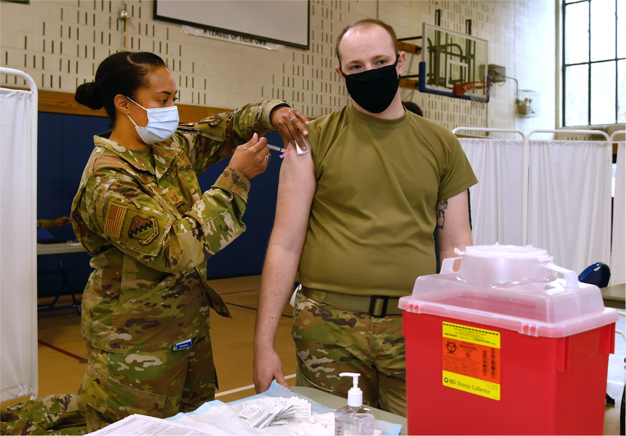 Senior Airman Brett Einsidler, 66th Medical Squadron Public Health technician, receives the COVID-19 vaccine from Tech. Sgt. Sherie Gregory, 66 MDS Flight Chief Aerospace, at Hanscom Air Force Base, Mass., Jan. 14. (U.S. Air Force photo by Linda LaBonte Britt)