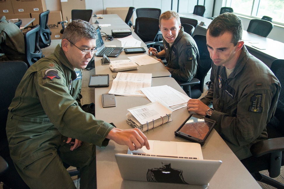 U.S. Air Force Maj. Joseph Yasunaga (left), Pilot Training Next instructor pilot, teaches 2nd Lts. Nickolas Brandt and John Massey, PTN students, flying techniques at the Armed Forces Reserve Center in Austin, Texas, June 21, 2018.