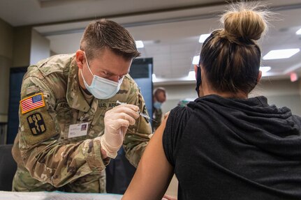 Michigan Army National Guard Sgt. Mark Abbott administers a COVID-19 vaccine to a health care worker at the Ascension Providence Rochester Hospital, Rochester, Michigan, Dec. 21, 2020. The Michigan Army National Guard is part of a nationwide National Guard effort that involves collecting, securing, transporting and – when requested – administering COVID-19 vaccinations.