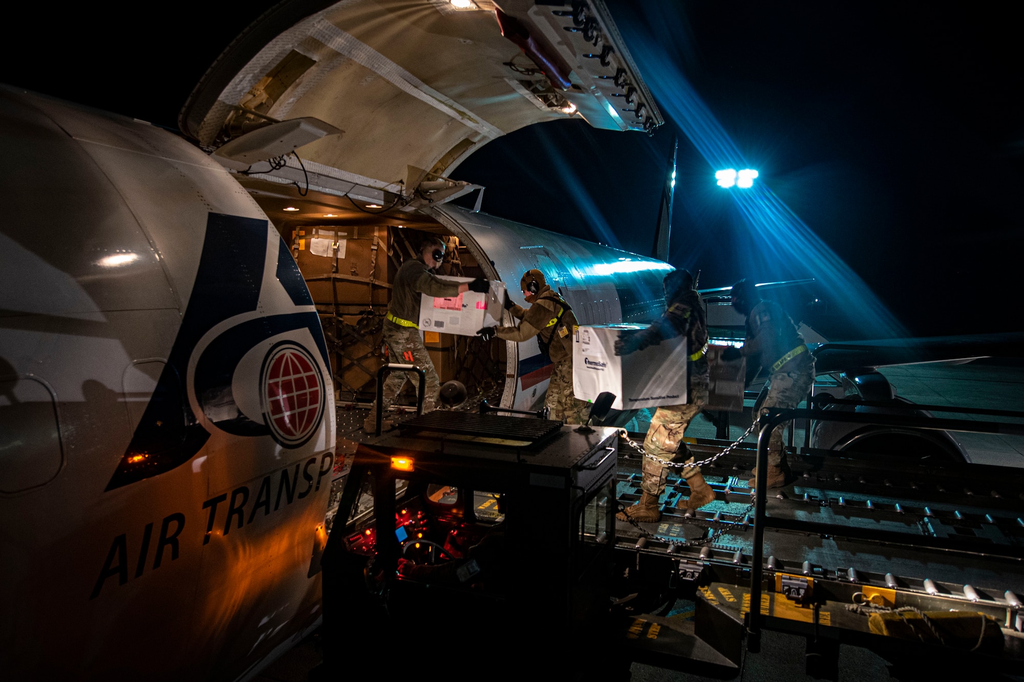 Photo of Airmen assigned to the 305th Aerial Port Squadron loading the COVID-19 vaccine onto a Boeing 757 assigned to Air Transport International.