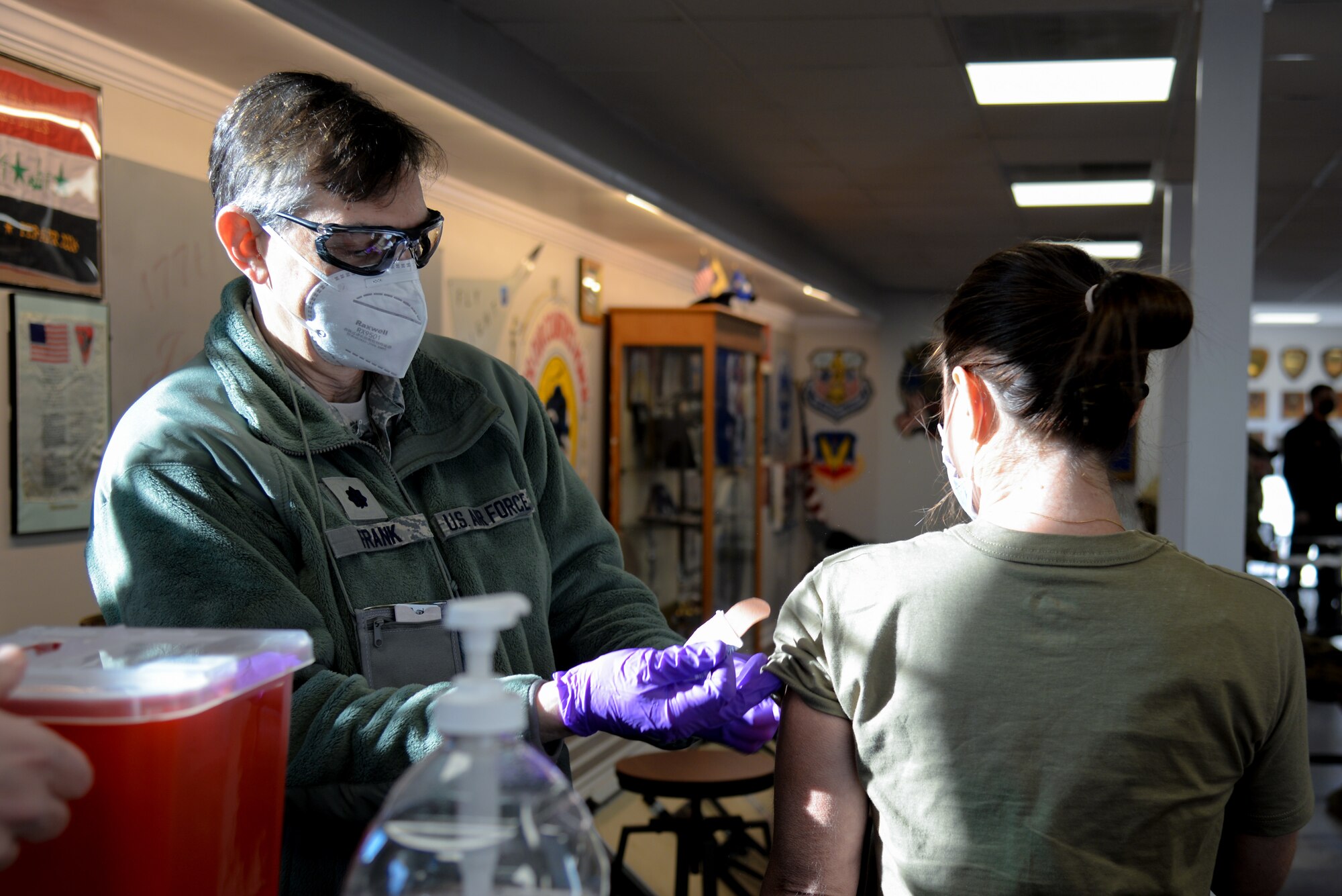 A photo of Lt. Col. Ronald M. Frank administering a COVID-19 vaccine to Lt. Col. Jessica Bramlette,