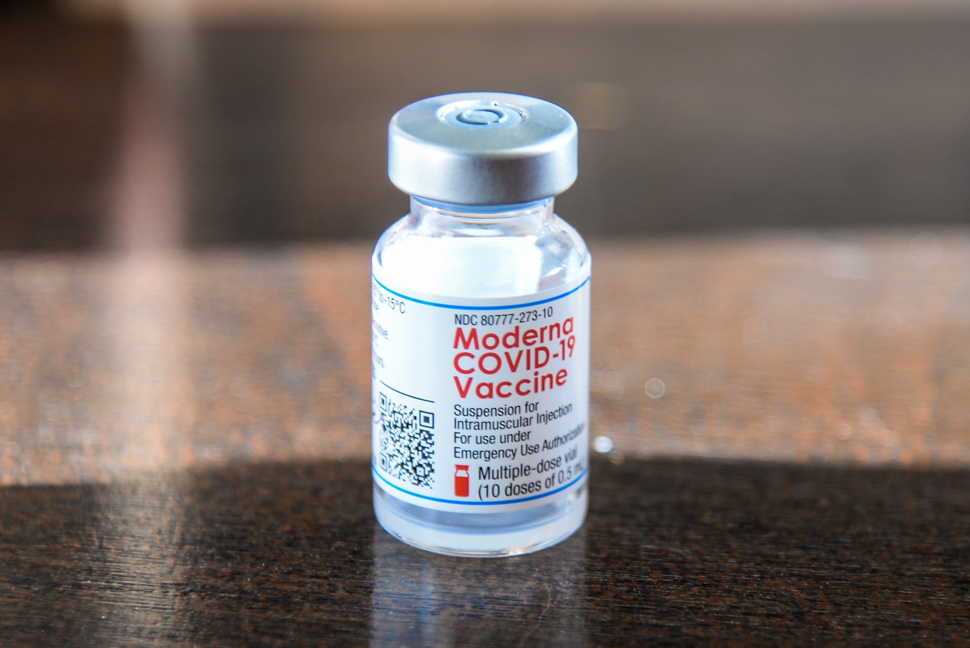 A photo of a vial of the Moderna COVID-19 vaccine sitting on a table