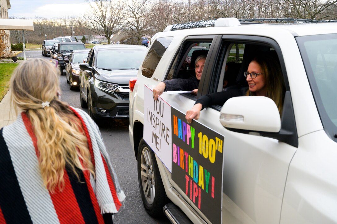 Well-wishers hold up signs Dec. 23, 2020, wishing Tipi Minnehan a happy 100th birthday. Friends and family, in a long line of cars, drove past the World War II Army veteran’s residence in Fairborn, Ohio, to safely wish her well. (U.S. Air Force photo by R.J. Oriez)