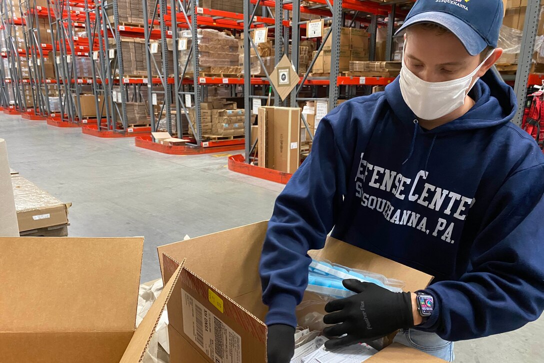 A man packs boxes with medical supplies.