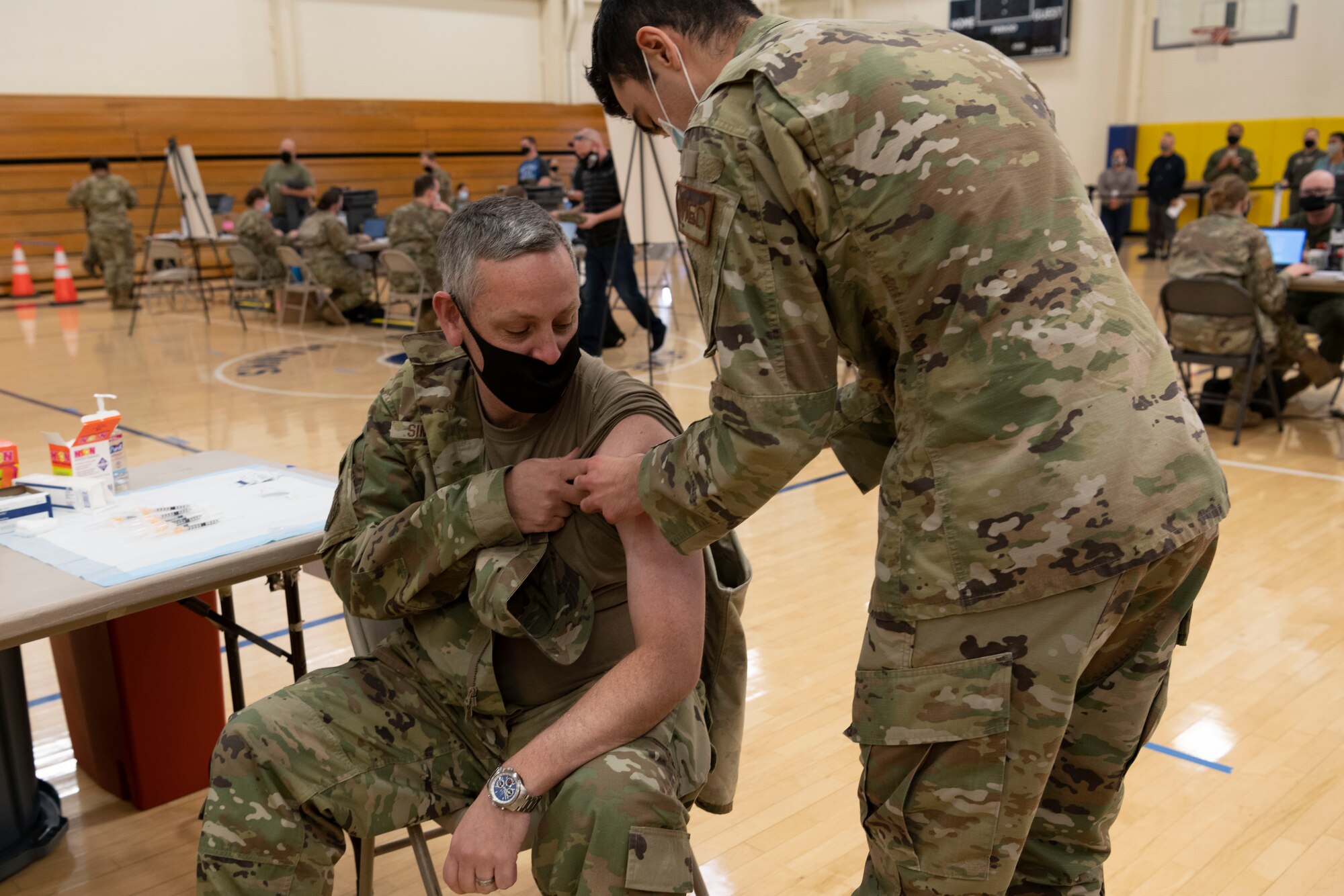 U.S. Air Force A1C Tyler Lancaster, 60th Healthcare Operations Squadron, medical technician, administers an initial COVID-19 vaccine to Col. Corey Simmons, 60th Air Mobility Wing commander, Dec. 29, 2020 at Travis Air Force Base, California. The vaccine requires two doses per person, separated by about four weeks between doses. It is designed to protect against the coronavirus, and officials are encouraging all prioritized personnel to take the vaccine as it becomes available. (U.S. Air Force photo by Airman 1st Class Alexander Merchak)