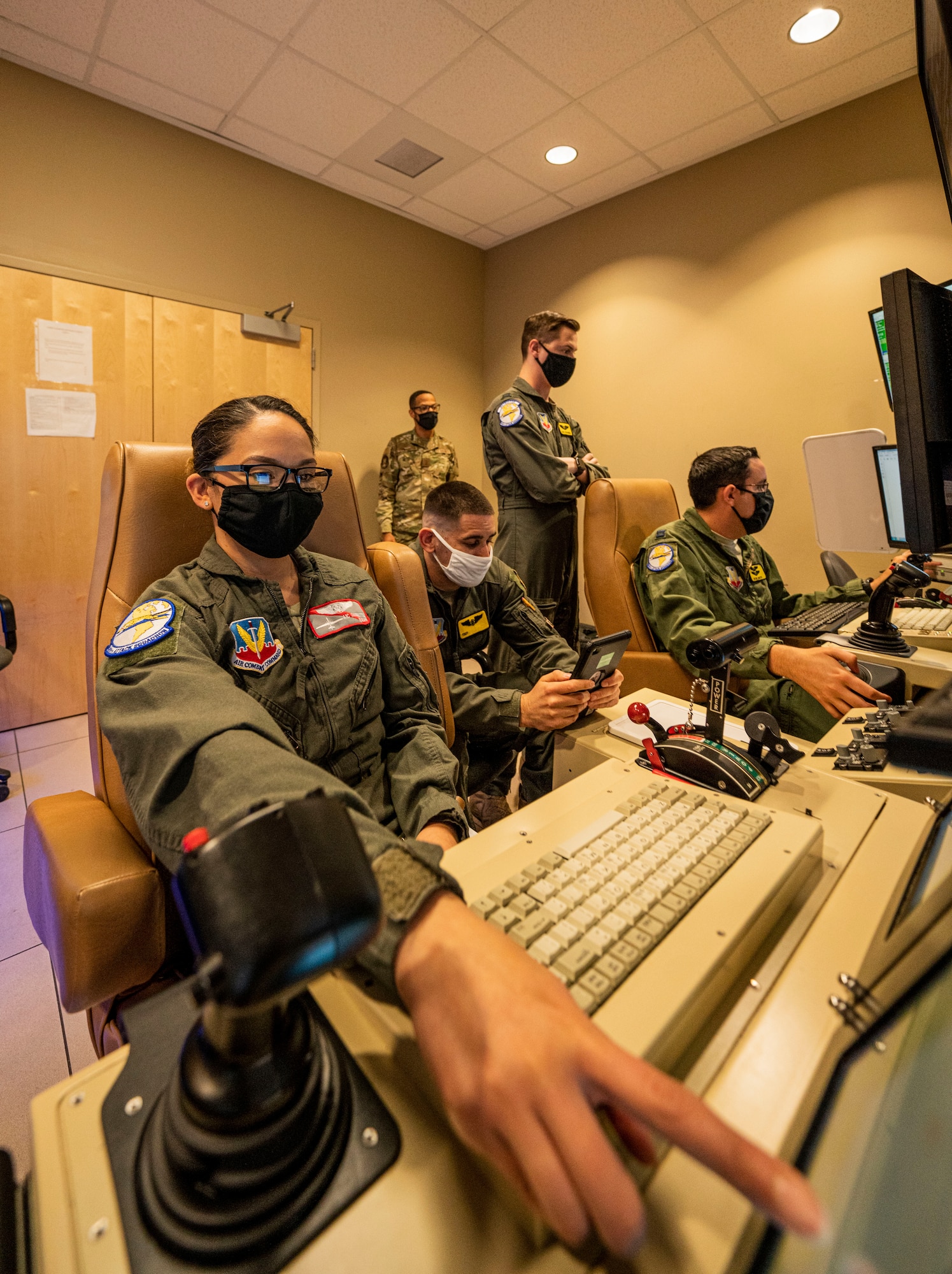 An airman points at one of her monitors before a sortie in a simulator.