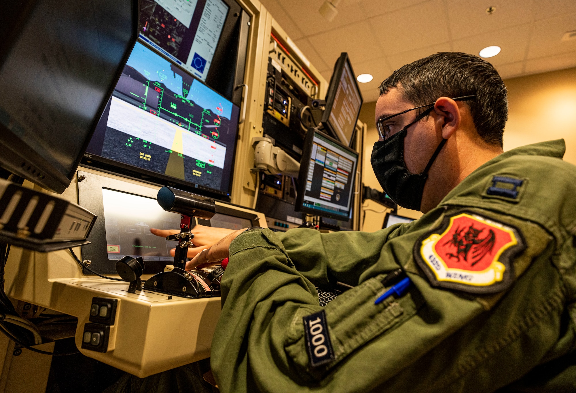 A pilot points at one of his monitors in a simulator.