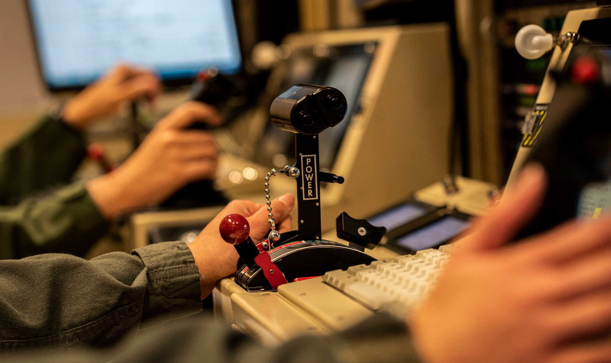 An airman's hand rests beside simulator controls.