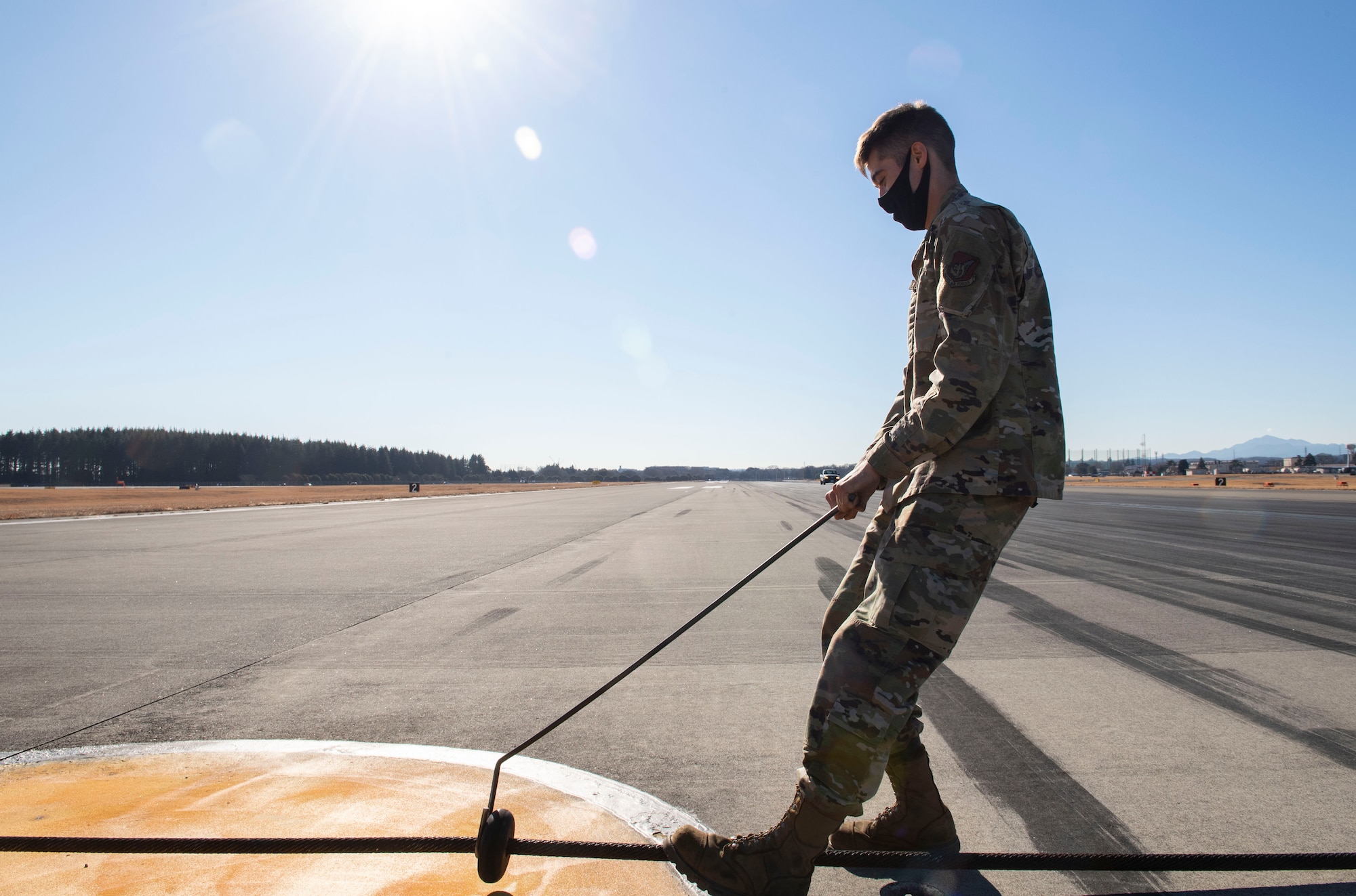 Airman Eric Christenson, 374th Civil Engineer Squadron electrical power productions shop apprentice, ensures precise spacing in-between cable donuts prior to the certification test of the newly installed flightline BAK-12 barrier, aircraft arresting system (AAS)