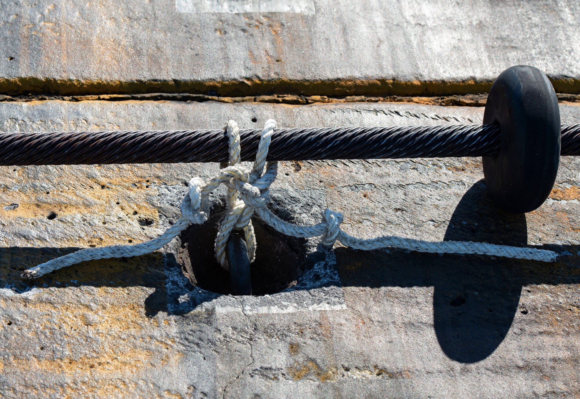 A flightline BAK-12 barrier, aircraft arresting system (AAS) cable is tied to a spot on the runway