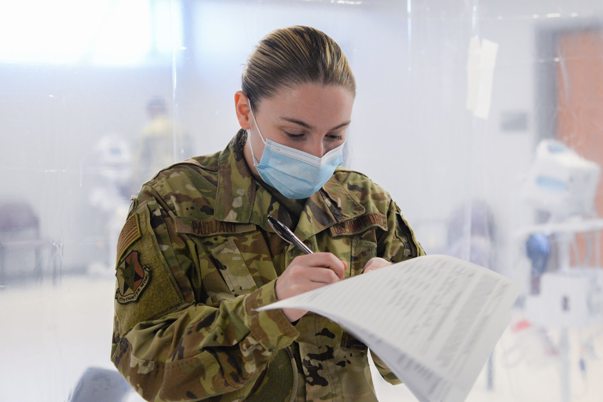 U.S. Air Force Airman lauren A. Paduani, 177th Logistics Readiness Squadron traffic management office specialist, completes paperwork during her out-processing Jan. 13, 2021, at the New Jersey National Guard Base, Sea Girt, N.J. The out-process included a briefing, medical examinations and a sit-down with administration. (U.S. Air National Guard photo illustration by Airman 1st Class Hunter Hires)
