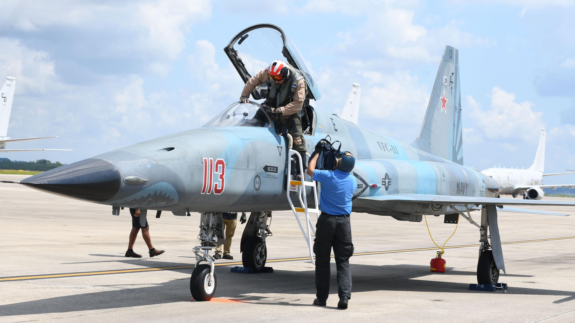 A pilot is assisted in exiting a small fighter jet
