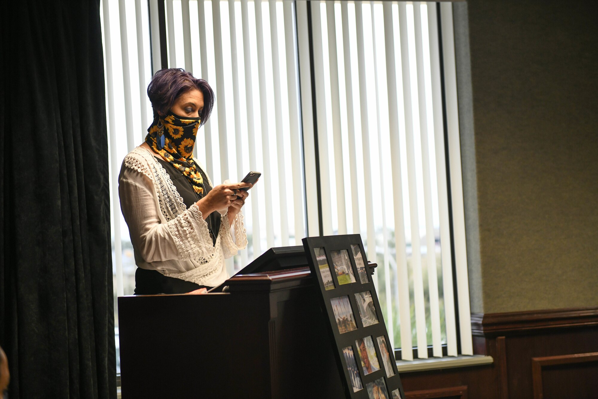 A woman stands at a podium, reading a speech from her phone.