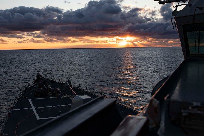 The sun hits the horizon on the ocean as  seen from a ship.