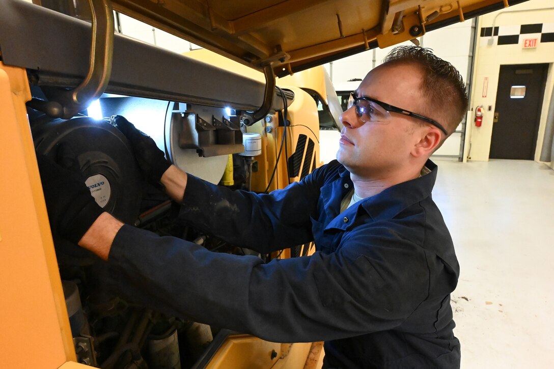 Airman Tech. Sgt. Casey Schroeder, of the 119th Logistics Readiness Squadron, reaches into the engine area of a payloader to change the air filter for equipment maintenance at in a garage at the North Dakota Air National Guard Base, Fargo, N.D., Jan. 6, 2021.