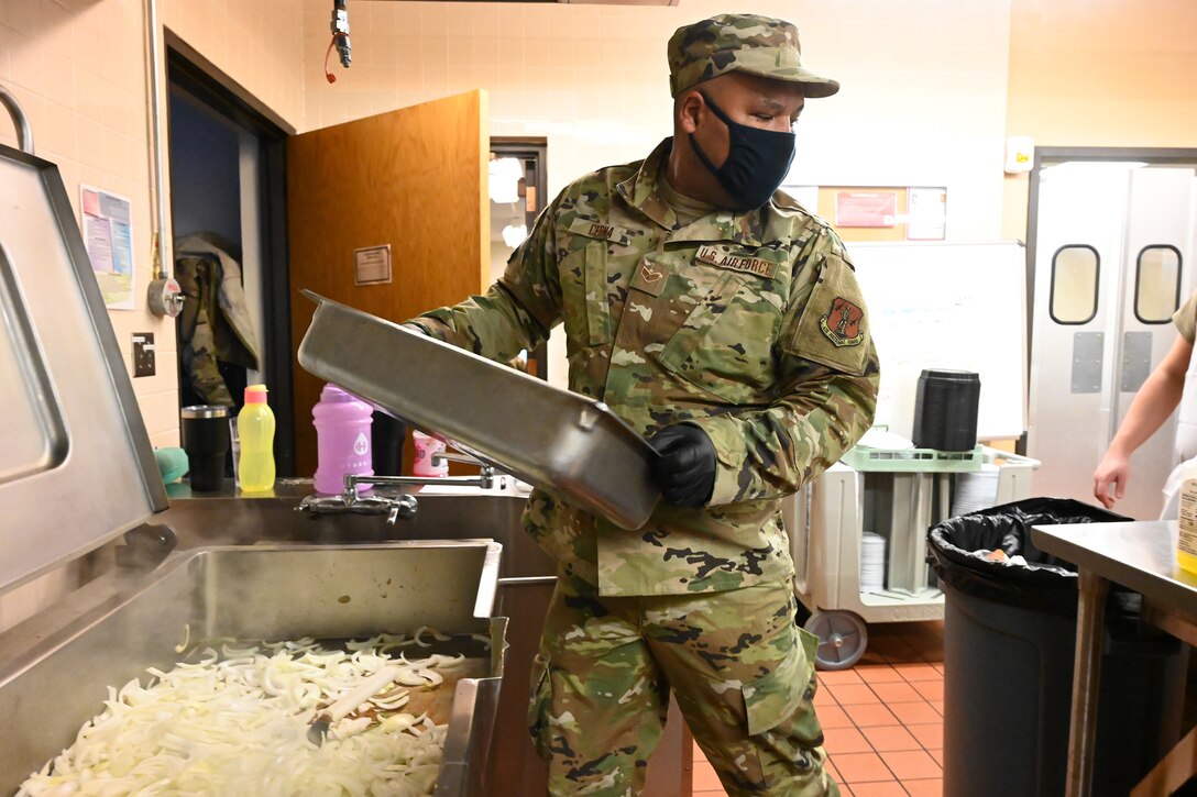 An Airman in uniform moves a cooking pan in a kitchen area at the North Dakota Air National Guard Base, Fargo, N.D., Jan. 10, 2021.