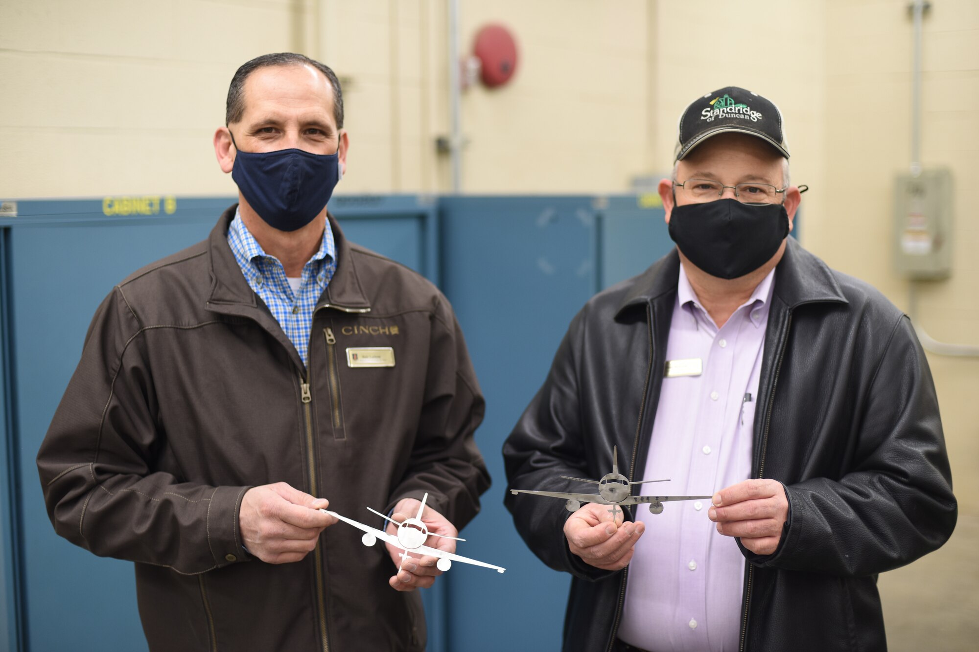 Two men hold miniature planes