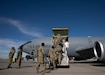 Soldiers walk up stairs to plain.