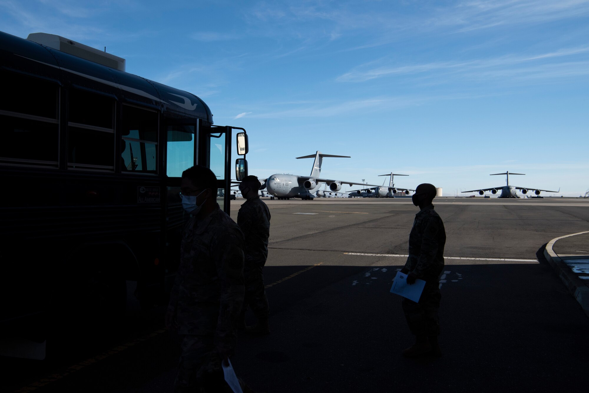 U.S. Airmen board a bus to travel from the influenza vaccine point of distribution in a hangar Jan. 14, 2021, at Travis Air Force Base, California. The POD is an organized way of efficiently distributing a vaccine to a large amount of people and preparing medical personnel for future large-scale distributions such as the COVID-19 Vaccine. (U.S. Air Force photo by Airman 1st Class Alexander Merchak)