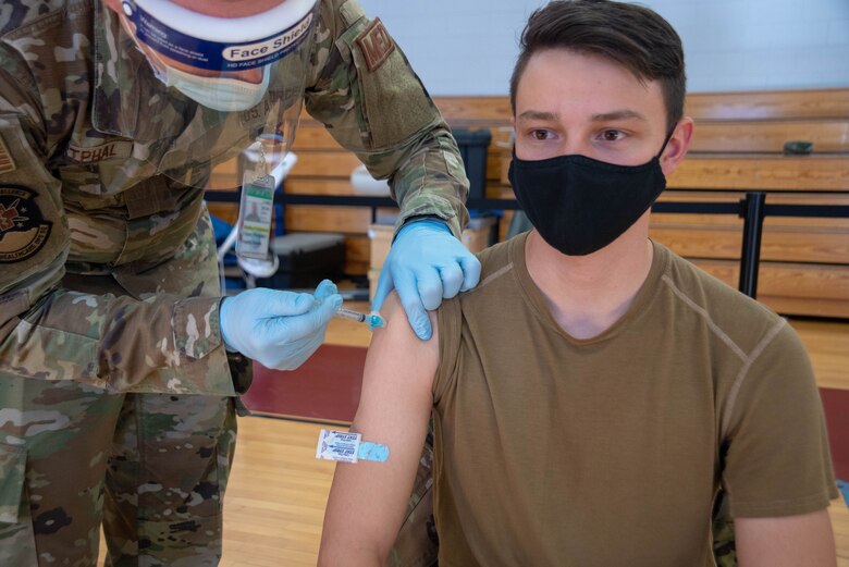 Military member receives vaccine shot in his shoulder.