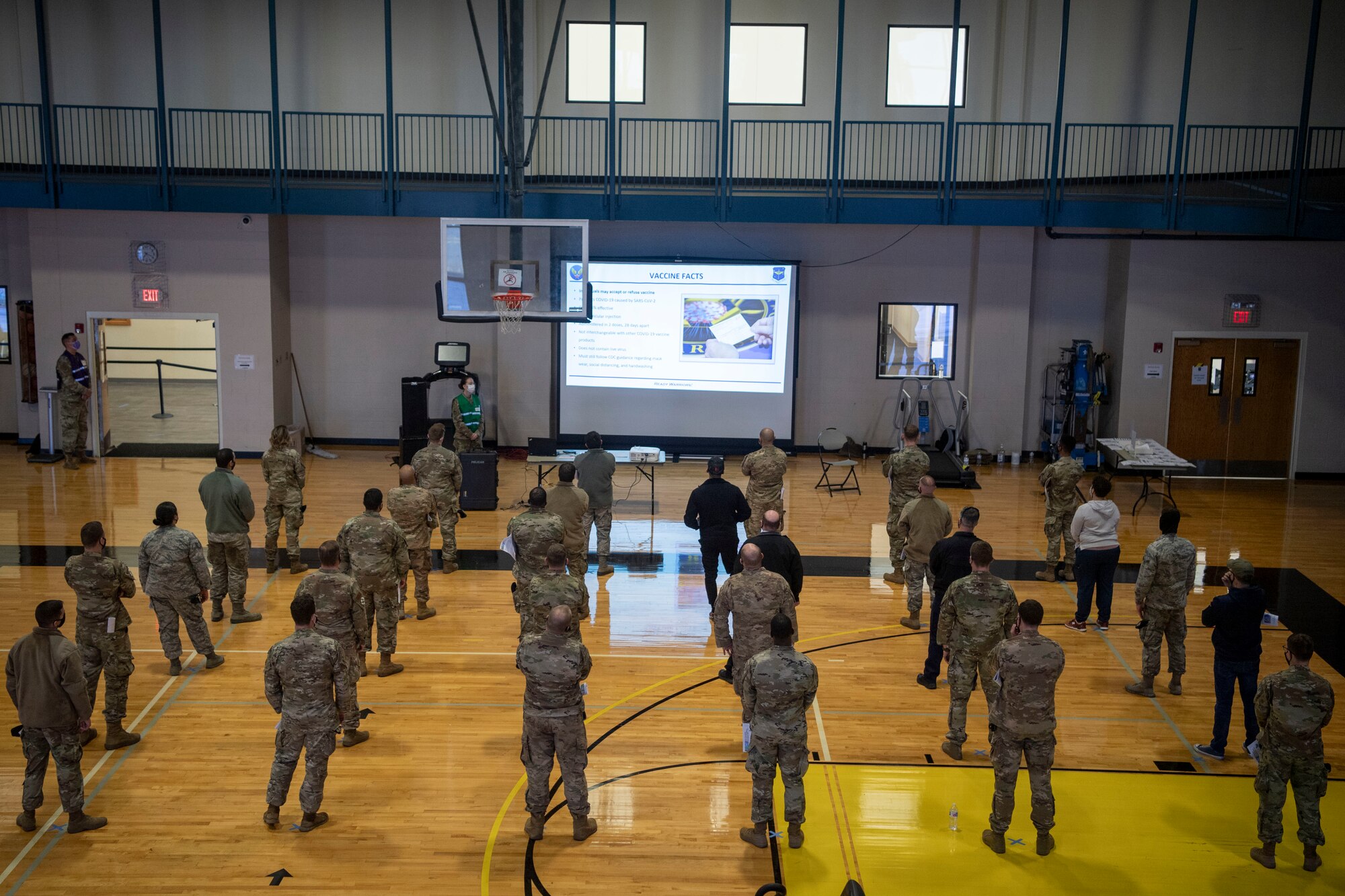 Airmen stand in the gym prior to getting a COVID-19 vaccine.
