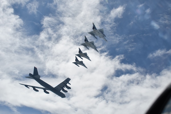 One large and four small airplanes fly in the sky.